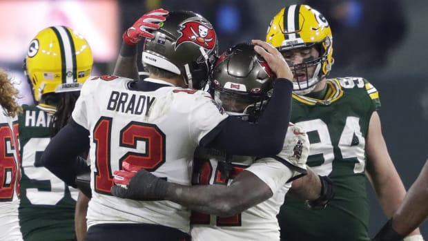 Tampa Bay Buccaneers quarterback Tom Brady hugs running back Ronald Jones with Packers players in the background