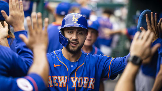 Mets outfielder Michael Conforto high-fives teammates in a dugout after scoring a run.