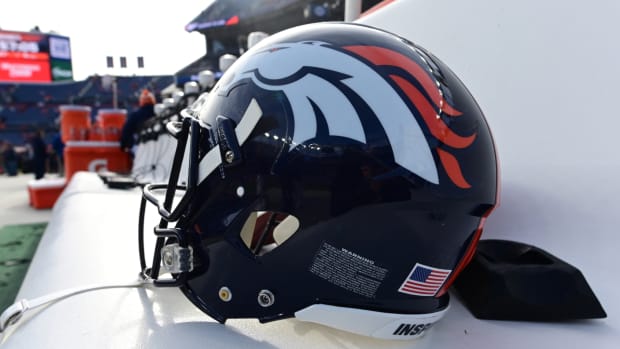 A close-up view of a Broncos helmet on the sideline.