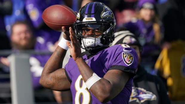 Baltimore Ravens quarterback Lamar Jackson throws a ball with a helmet and uniform on during warmups
