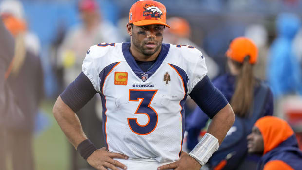 Broncos quarterbacks Russell Wilson looks on from the sidelines with his hands on his hips during a game.