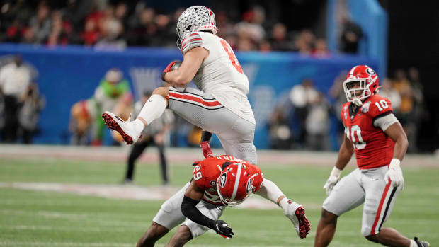 Dec 31, 2022; Atlanta, Georgia, USA; Ohio State Buckeyes tight end Cade Stover (8) goes airborne over Georgia Bulldogs defensive back Christopher Smith (29) during the first quarter of the 2022 Peach Bowl at Mercedes-Benz Stadium.