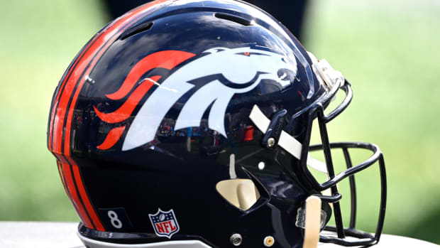 A close-up view of a Broncos helmet on the sidelines.