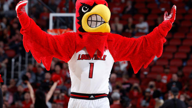The Louisville mascot raises his hands during a basketball game.