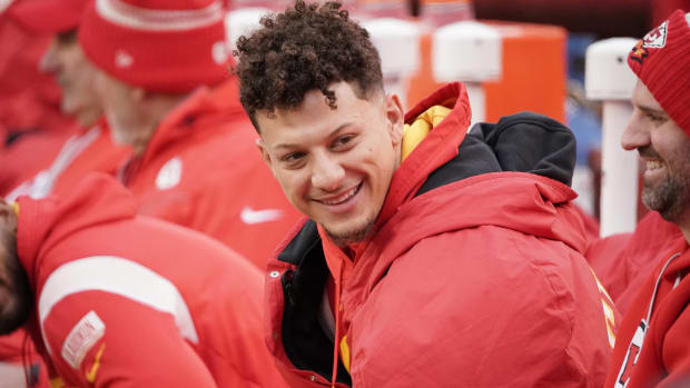 Chiefs quarterback Patrick Mahomes smiles on the sideline during a game.
