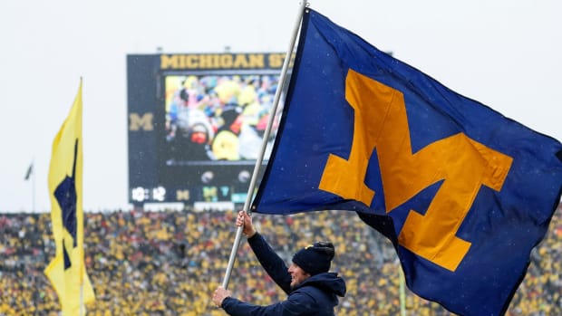 A member of the Michigan spirit squad holds a Michigan flag during a football game.