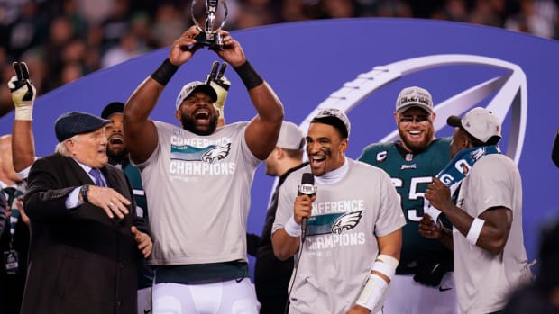 Terry Bradshaw, left, reacts as Philadelphia Eagles defensive tackle Fletcher Cox, second from left, hoists the George Halas Trophy as quarterback Jalen Hurts, center, holds a microphone after the NFC Championship NFL football game between the Philadelphia Eagles and the San Francisco 49ers on Sunday, Jan. 29, 2023, in Philadelphia. The Eagles won 31-7. (AP Photo/Seth Wenig)