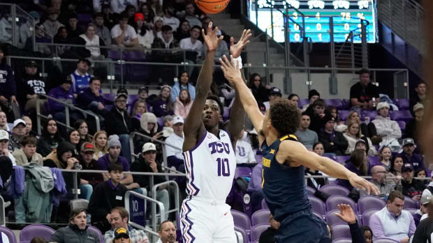 Jan 31, 2023; Fort Worth, Texas, USA; TCU Horned Frogs guard Damion Baugh (10) scores a three-point basket against West Virginia Mountaineers forward Tre Mitchell (3) during the first half at Ed and Rae Schollmaier Arena.