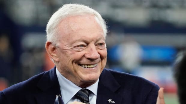 Cowboys owner Jerry Jones speaks with people on the field at AT&T Stadium before a game.
