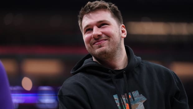 Mavericks guard Luka Dončić smiles while on the sidelines while inactive before a game.