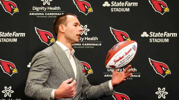 Jonathan Gannon tosses a football in the air during his introductory press conference