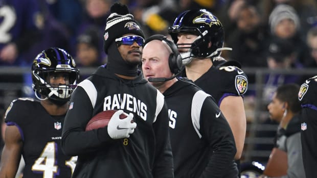 Lamar Jackson stands on the sideline during a Ravens game he missed due to injury