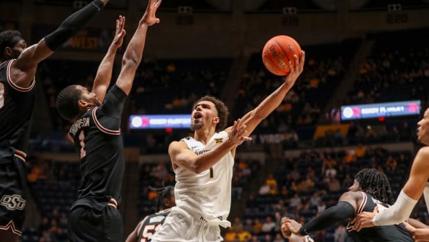 Feb 20, 2023; Morgantown, West Virginia, USA; West Virginia Mountaineers forward Emmitt Matthews Jr. (1) shoots in the lane over Oklahoma State Cowboys guard Bryce Thompson (1) during the second half at WVU Coliseum.