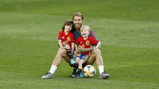 Sergio Ramos y sus hijos con la camiseta de la selección española sentados en el pasto.