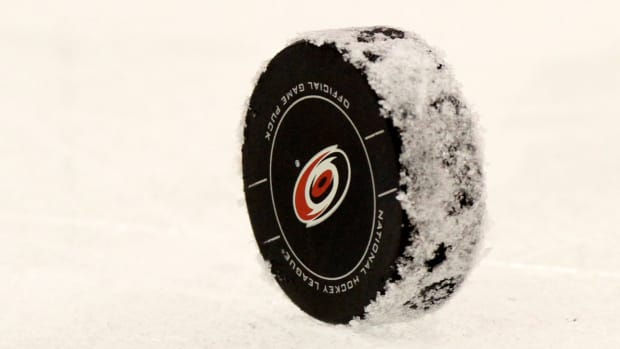 A puck with the Carolina Hurricanes logo is shown on the ice.