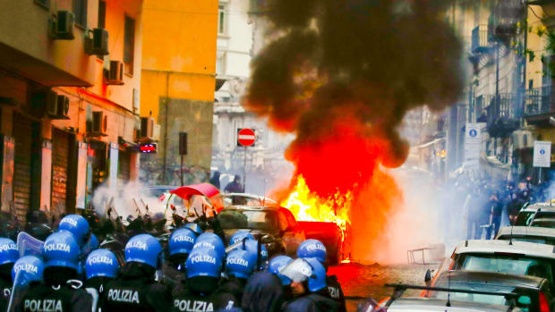 A car is pictured on fire in the city of Naples amid clashes between fans from Eintracht Frankfurt and local police in March 2023
