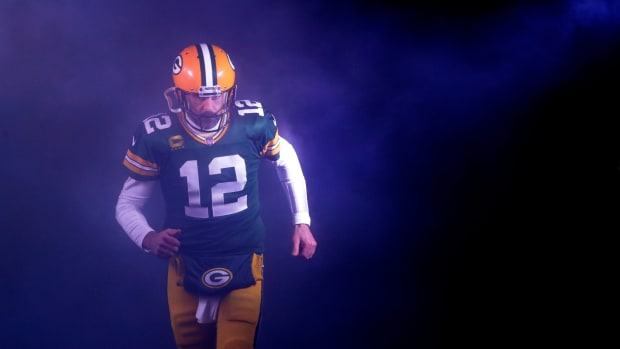 Aaron Rodgers en uniforme de Packers corre por el humo