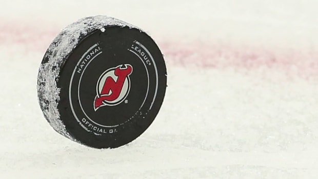 An NHL puck with the New Jersey Devils logo on it slides across the ice.