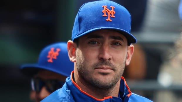 Former Mets pitcher Matt Harvey looks on while in a dugout during a Mets game.