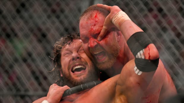 Kenny Omega pokes a bloody Jon Moxley in the eye