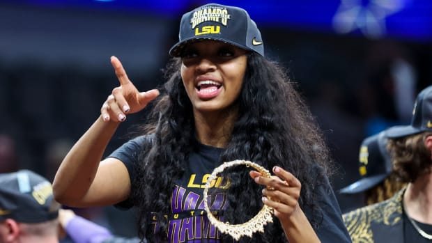 LSU Lady Tigers forward Angel Reese points while holding a crown in one hand