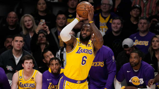 Lakers forward LeBron James shoots while several of his teammates look from the bench behind him