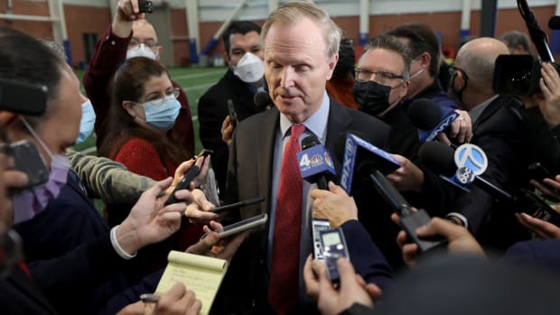 Giants co-owner John Mara speaks as a circle of reporters hold up microphones