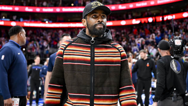 Mavericks point guard Kyrie Irving walks off the court in street clothes after a game.