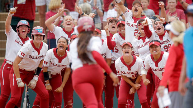 The Oklahoma Sooner softball team celebrates while waiting for Cydney Sanders to touch home plate following a home run.