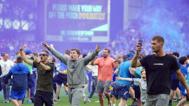 Everton fans pictured on the pitch at Goodison Park after watching their team beat Bournemouth 1-0 to avoid relegation from the Premier League in May 2023