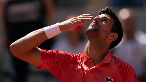 Novak Djokovic brings his hand to his mouth as he looks up to the sky