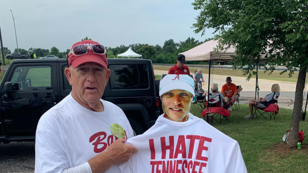 A family member for Alabama softball player Emma Broadfoot holds up a cutout of Emma's brother Jackson, a med student who couldn't be in Oklahoma City for the Women's College World Series.