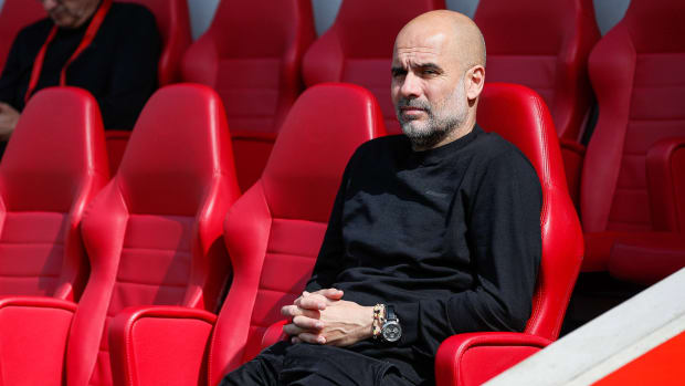 Man City manager Pep Guardiola sits before a game vs. Brentford.