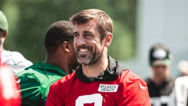 Jets' QB Aaron Rodgers smiling with his arms folded