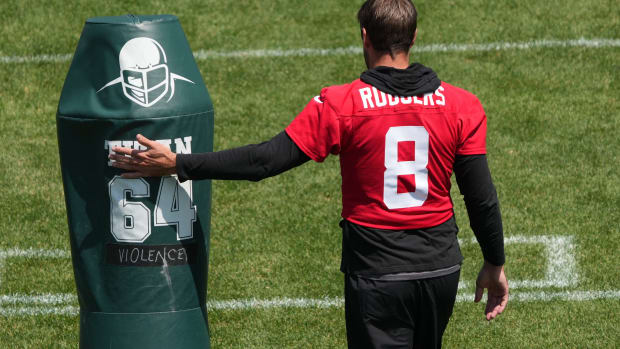 QB Aaron Rodgers walks by a tackling dummy at Jets' OTAs