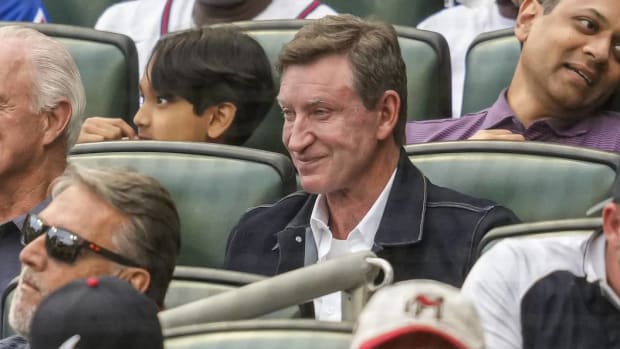 NHL great Wayne Gretzky watches a baseball game between the Dodgers and Braves from the stands.