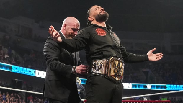 Triple H presents Roman Reigns with his new championship belt