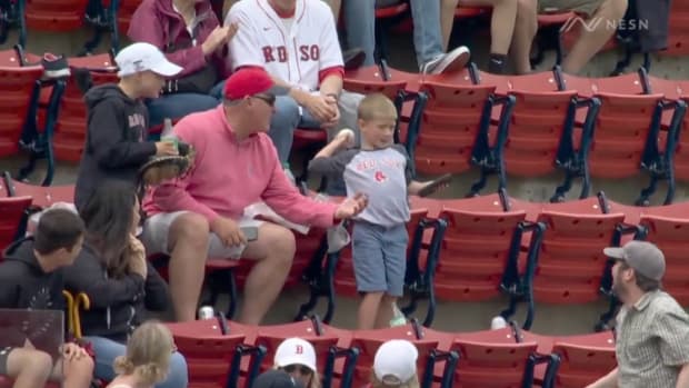 A Red Sox fan hands a foul ball to a young fan at Fenway Park.