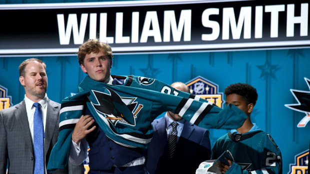 William Smith puts on a San Jose Sharks sweater after being selected with the fourth pick in round one of the 2023 NHL Draft at Bridgestone Arena.