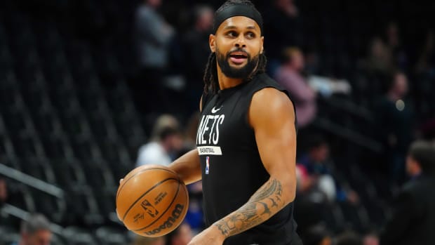 Nets point guard Patty Mills dribbles a ball in warmups before a game.