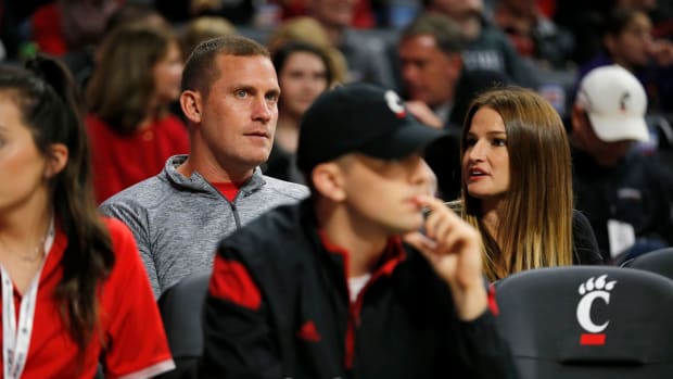 Former Bearcats punter Kevin Huber watches from floor seats with his wife Mindi in the first half of an exhibition game between the University of Cincinnati Bearcats and the Tusculum Pioneers at Fifth Third Arena on the University of Cincinnati campus in Cincinnati on Tuesday, Oct. 16, 2018. Tusculum Pioneers At Cincinnati Bearcats