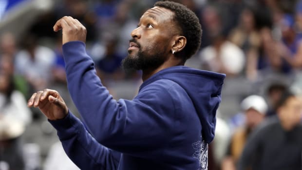 Mavericks point guard Kemba Walker warms up in a sweatshirt during halftime of a game.