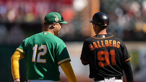 Mar 26, 2023; Oakland, California, USA; Oakland Athletics left fielder Aledmys Diaz (12) converse with San Francisco Giants third base coach Mark Hallberg (91) during the sixth inning at RingCentral Coliseum. Mandatory Credit: Stan Szeto-USA TODAY Sports