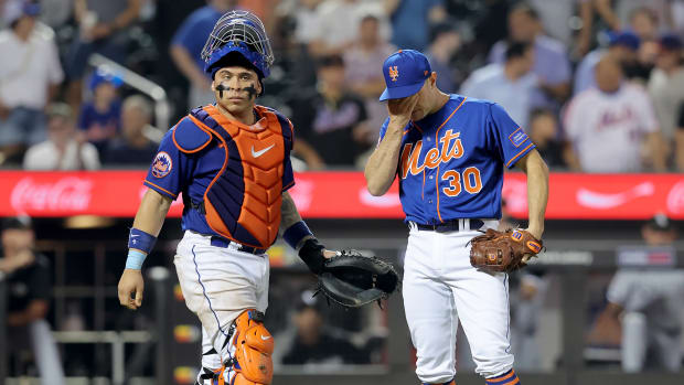New York Mets relief pitcher David Robertson puts his hand on his face as catcher Francisco Alvarez walks over to talk to him