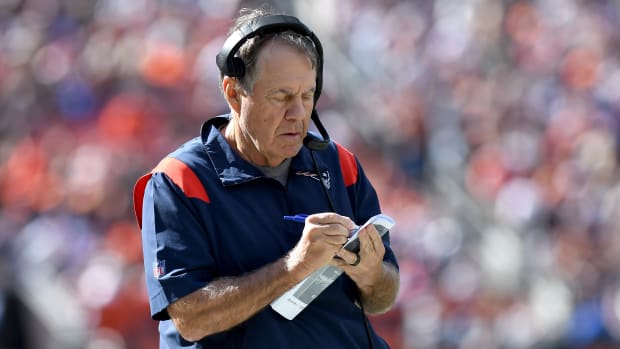 Bill Belichick writes on a piece of paper while wearing a headset