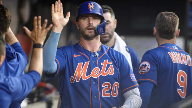 Mets first baseman Pete Alonso high fives teammates in the dugout during a game.