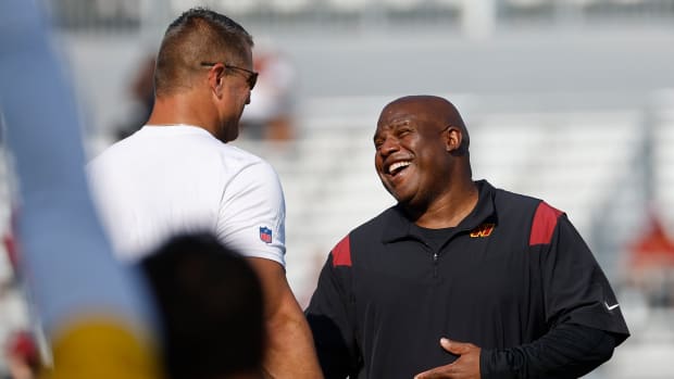Washington Commanders assistant head coach/offensive coordinator Eric Bieniemy (R) jokes with Commanders defensive line coach Jeff Zgonina (L) during warmup on day three of Commanders training camp at OrthoVirginia Training Center