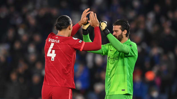 Virgil van Dijk (left) pictured exchanging high fives with Alisson Becker during Liverpool's game at Leicester in December 2021
