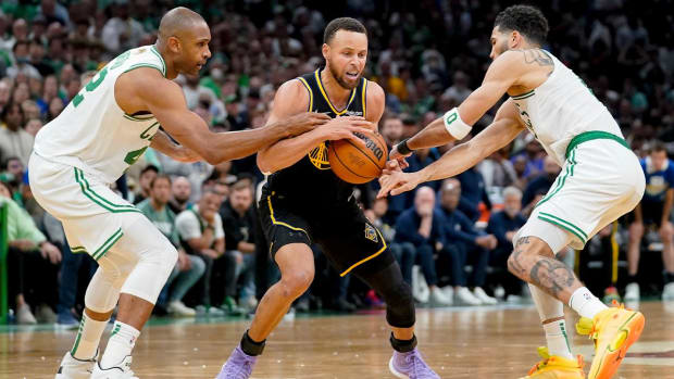 Golden State Warriors guard Stephen Curry (30) is double teamed by Boston Celtics center Al Horford (42) and forward Jayson Tatum (0) during the fourth quarter of Game 4 of basketball’s NBA Finals, Friday, June 10, 2022, in Boston.