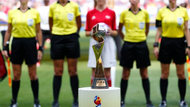 The FIFA Women’s World Cup Trophy in front of players lined up.